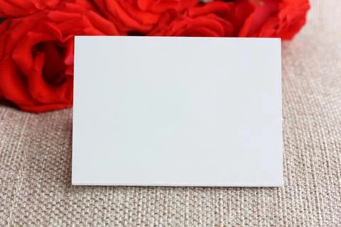 Empty paper card close-up and red roses. Stock Photos
