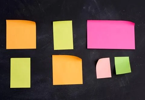 Empty paper multi-colored stickers are glued on a black board Stock Photos