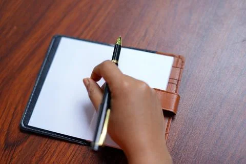 Empty paper note book with female hand holding pen. image Stock Photos