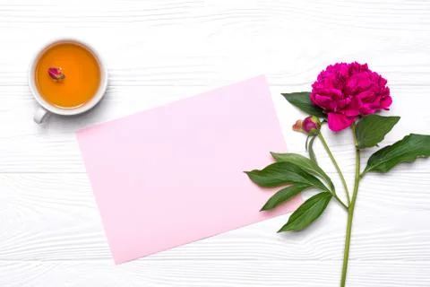 Empty paper with place for text, a cup of tee and peony flower on a white woo Stock Photos