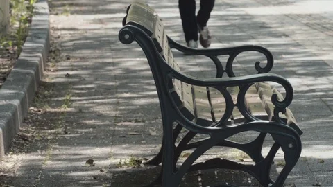 Empty park bench and a man walking in sunny, spring day Stock Footage 75347413