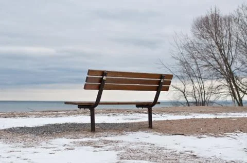 Empty Park Bench by a Lake in Winter Stock Photos