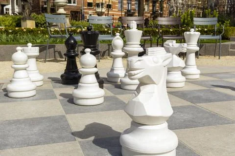 Empty park with big chess figures and empty chairs on background.Nobody playi Stock Photos