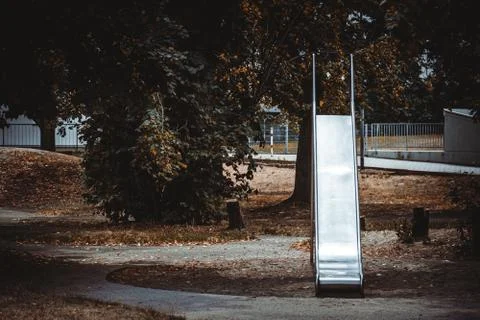 Empty park with a slide surrounded by trees on a sunny day Stock Photos
