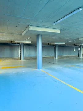 Empty parking garage with blue floor and concrete structure during daylight Stock Photos