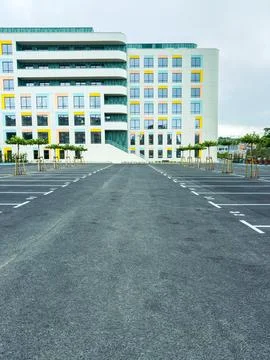 Empty parking lot in front of a modern building during a cloudy day with fe.. Stock Photos