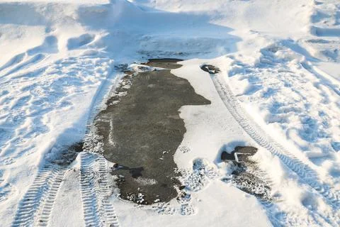 An empty parking space without snow where a car was parked recently Stock Photos
