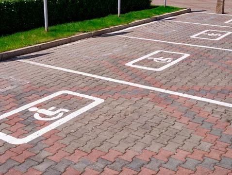 Empty parking spaces marked for accessibility in a community lot during daytime Stock Photos