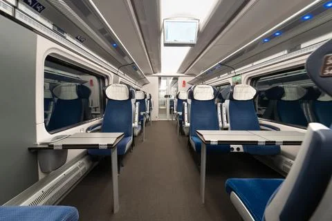 Empty passenger train carriage interior with rows of seats and tables Stock Photos
