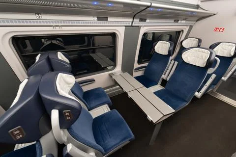 Empty passenger train interior with blue seats and table by large window Stock Photos