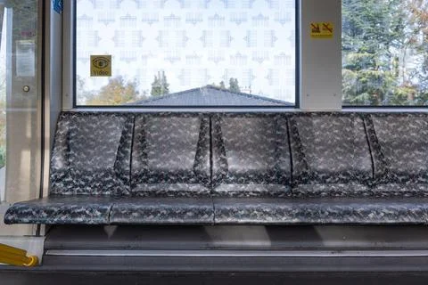 Empty patterned seats inside a public train are illuminated by daylight. Stock Photos
