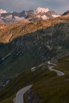Empty paved mountain road winding through the landscape. In a small dirt Stock Photos