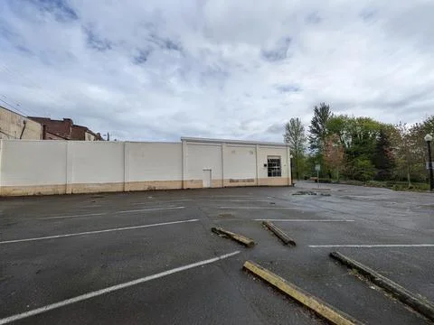 Empty paved parking lot beside a plain white industrial building Stock Photos