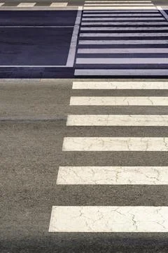 Empty pedestrian crosswalk with dramatic diagonal shadow creates abstract Stock Photos