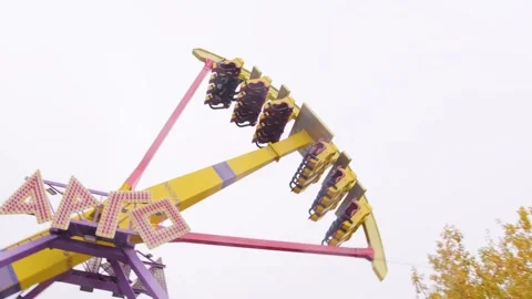 An empty pendulum ride attraction spins in a circle on a cloudy day in autumn Stockbeeldmateriaal 254115883