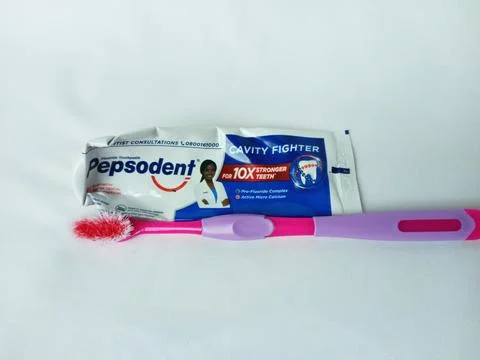 Empty Pepsodent toothpaste tube, used toothbrush on white background. Stock-Fotos