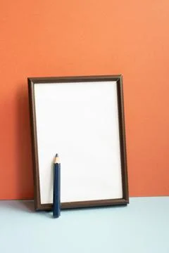 Empty photo frame with colored pencil on gray shelf. red wall background Foto stock