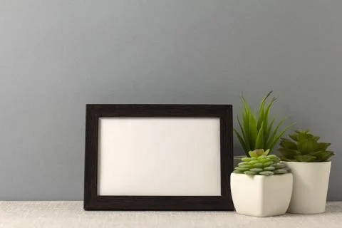 An empty photo frame on the table. Mini pots with succulents. A minimalist-st Stock Photos