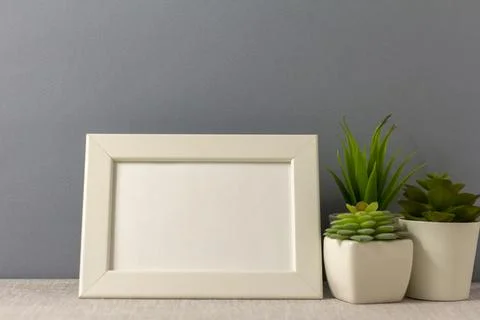 An empty photo frame on the table. Mini pots with succulents. A minimalist-.. Stock Photos