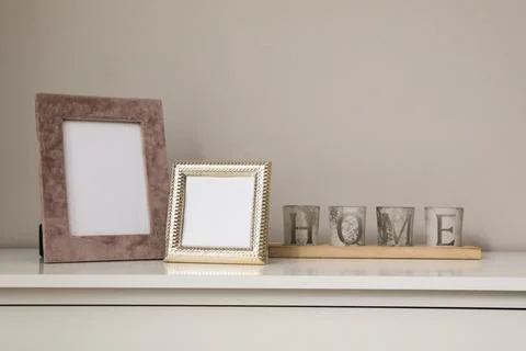 Empty photo frames and candles on table indoors, space for text Stock Photos