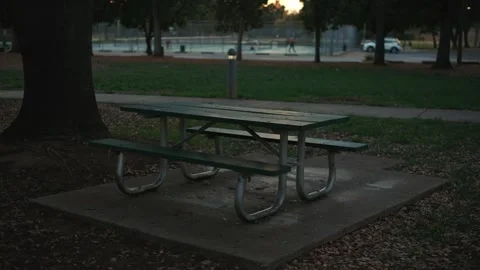 Empty picnic table near tennis courts in a city park at sunset Видео 325686271