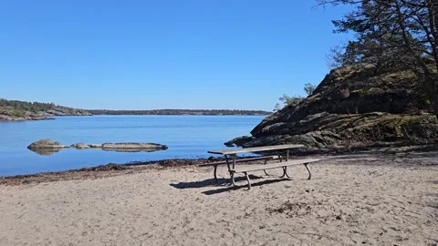 Empty Picnic Table on Sandy Beach Overlooking Calm Coastal Waters Stock Footage 333846063