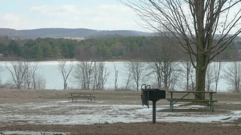 Empty Picnic Tables at Park in Winter with Lake in Background PAN RIGHT Video stock 104725028