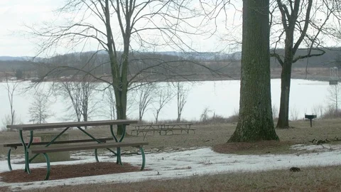 Empty Picnic Tables at Park in Winter with Lake in Background PAN LEFT Video stock 104725996