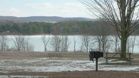 Empty Picnic Tables at Park in Winter with Lake in Background PAN RIGHT Video stock 104726173