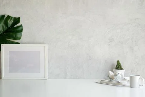 Empty picture frame, cactus, coffee cup and headphone on white table. Stock Photos