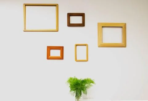 Empty picture frames on white wall and fern leaves in glass on the table Stock Photos