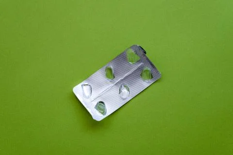 Empty pill blister pack on a green background. Stock Photos