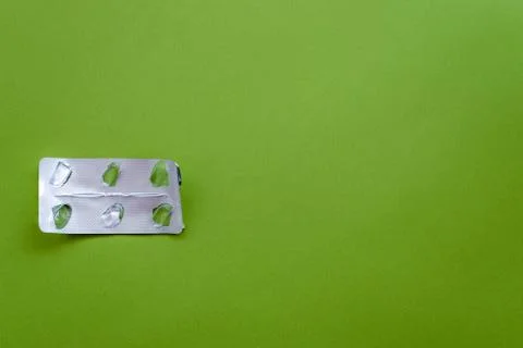 Empty pill blister pack on a green background. Stock Photos