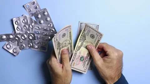 Empty pill blisters and man's hands counting American dollars (USD) banknotes. Stock Footage 303346370