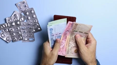 Empty pill blisters and man's hands counting Thai baht (THB) banknotes. Stock Footage 303357910