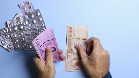Empty pill blisters and man's hands counting Thai baht (THB) banknotes. Stock Footage 303358241