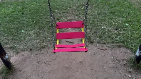 Empty pink and yellow swing seat hanging on metal chains at playground Vidéo 340514928