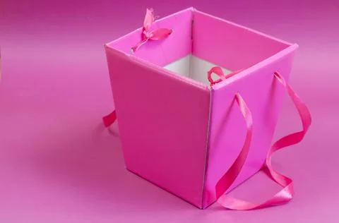 Empty pink gift box on a pink background. Cardboard box with tape handles. Mi Stock Photos