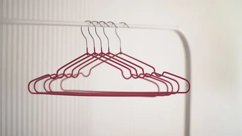 Empty pink hangers hang on white rack and sway in shop closeup. Stock Footage 139626850