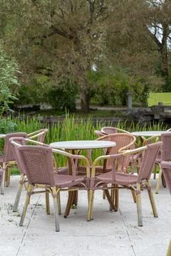 Empty pink wicker cafe chairs and tables beside reed pond Stock Photos