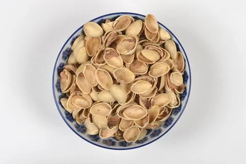 Empty pistachio nutshells in blue patterned ceramic bowl. Stock Photos