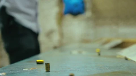 Empty pistol bullet shells dropping and impacting wooden table in a shooting  Stock Footage 128463829