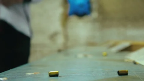 Empty pistol bullet shells dropping and impacting wooden table in a shooting  Stock Footage 128463933