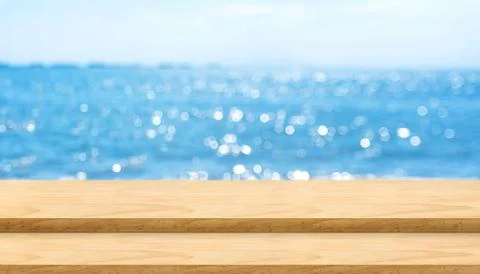 Empty plank wood table top with blur blue sky and sea bokeh background,Mock u Stock Photos