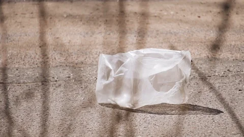 An empty plastic bag is lying on the road. Close up. Cars go by Stock Footage 128944874