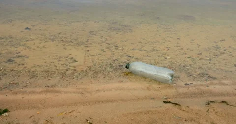 An empty plastic bottle bobs in the beach water Stock Footage 346451885