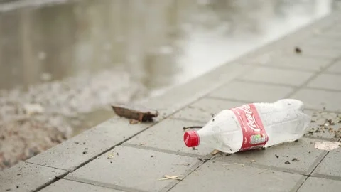 An empty plastic bottle of Coca-Cola is lying on the sidewalk. Pollution 스톡 동영상 166611229