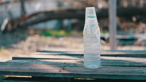 Empty Plastic Bottle with Cup on Top Standing on Wooden Table - Discarded Drink Stock Footage 305792586
