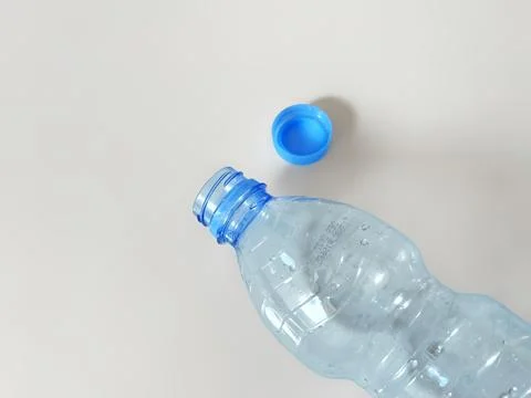 Empty plastic bottle with detached blue cap representing plastic recycling Stock Photos