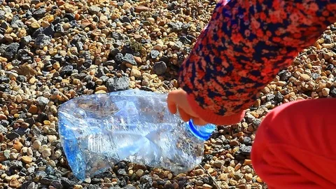 Empty plastic bottle stone background children hand hd footage Stock Footage 106391347
